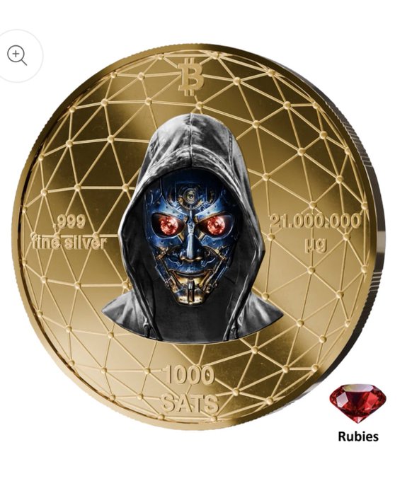 A gold commemorative coin featuring a robotic skull in a hooded cloak with red glowing eyes, marked '999 fine silver', '21,000,000 µƀ', '1000 SATS', with a Bitcoin symbol at the top and a 'Rubies' logo at the bottom right.