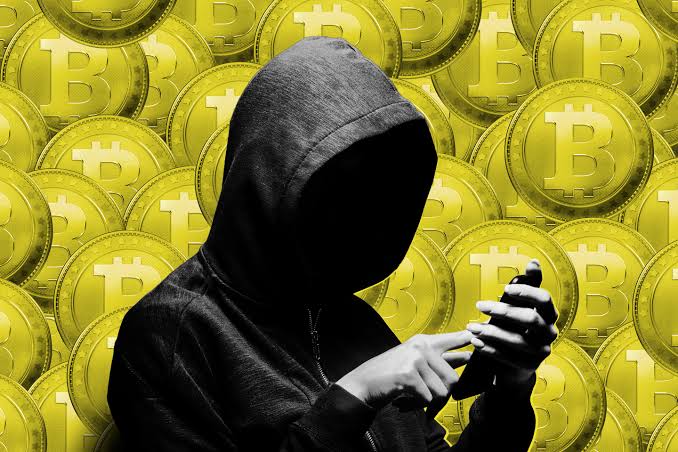 The image is a black and white illustration featuring an obscured person standing next to a wall of gold coins stacked on top of each other, with the individual partially hidden behind them. The main focus of the scene seems to be the person's hands holding their phone in the middle ground. The surrounding area has the word "FBI" printed at the bottom right corner of the image. In the background, there is text that reads: "FBI's Biggest Crypto Seizure Ever! May 28, 2006—Operation Blackout ↳ 127,000 $BTC segmented worth $8-15 Billion ↳ 300 arrests across 3 continents ↳ 2,000 trafficked workers rescued." This implies a connection to the FBI investigation surrounding a large cryptocurrency theft that affected numerous individuals.
