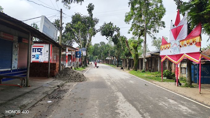 A quiet street scene in a rural town with closed shops, trees, and a decorative red and white archway on the right; watermarked "HONOR 400".