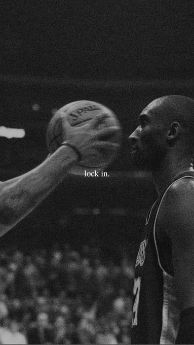A black-and-white photo of basketball player Kobe Bryant in his Lakers jersey, intensely staring at a Spalding basketball being held up, with the motivational text 'lock in.' overlaid in the center.