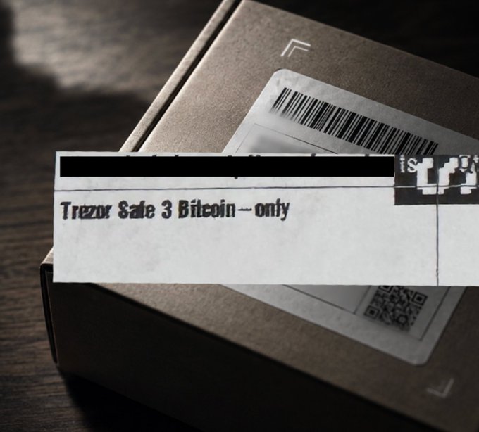 The image shows a cardboard package with a shipping label and barcode, overlaid with a news headline reading "Trezor Safe 3 Bitcoin—only." This relates to the post by illustrating the privacy concern where hardware wallet packaging visibly advertises its contents, potentially exposing users' crypto holdings and financial privacy to anyone handling the delivery.