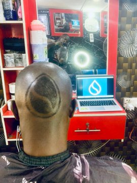 A surreal image shows a person with a reflective, metallic, teardrop-shaped head standing in front of a red vanity that holds a laptop displaying the Sui (SUI) logo.