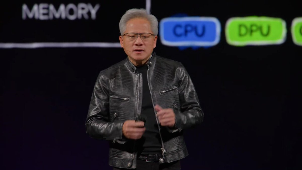 A man in a black leather jacket gives a presentation on stage, with a slide behind him displaying "MEMORY," "CPU," and "DPU" boxes.

The image appears to be unrelated to the accompanying post about the GOAT Network and agent infrastructure.