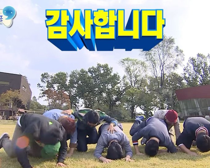 The image shows a group of people bowing on a grassy field, likely from a Korean variety show, with the text "감사합니다" (Thank you) prominently displayed above them, with a smiley face emoji in the corner. The humorous caption contrasts the formal, grateful bowing scene with the casual mention of receiving pay from Elon and buying Bitcoin, creating an ironic juxtaposition of traditional Korean gratitude with modern digital income.