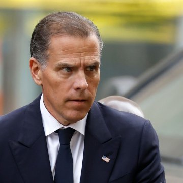 The image shows a man in a dark suit and navy tie, appearing to be Hunter Biden, with a concerned expression as he looks off to the side. It accompanies a post about a cryptocurrency called "$LAPTOP" experiencing a dramatic 90%+ crash, likely referencing the political context involving the Hunter Biden laptop story.