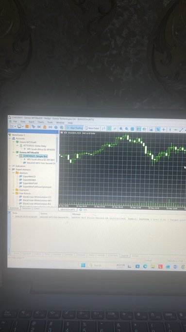A photo of a laptop screen displaying MetaTrader 5 with an XAUUSD M30 chart, dated 2024.09.26, showing green and red candles with various analysis tools open in the sidebar.