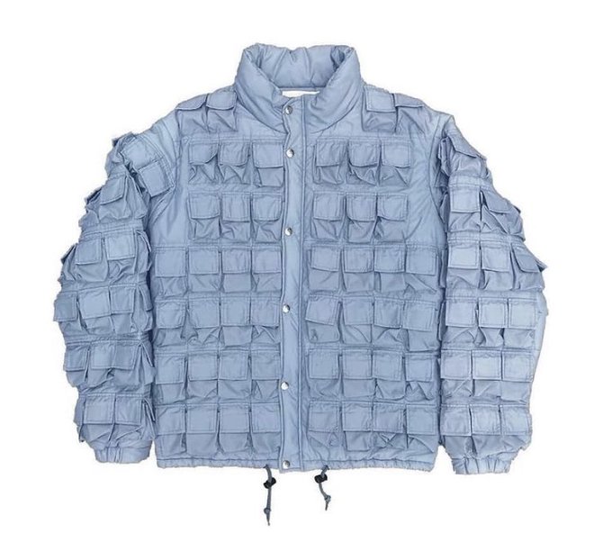 A light blue puffer-style jacket featuring a grid pattern of small pockets across the body and sleeves, with a button-up front closure.