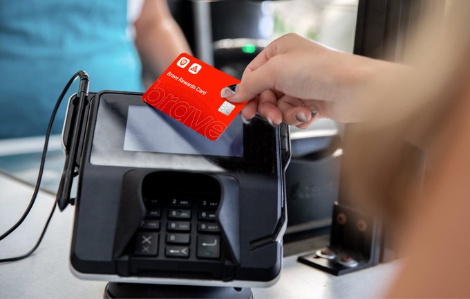 A person using a red 'Braavos Rewards Card' at a payment terminal.