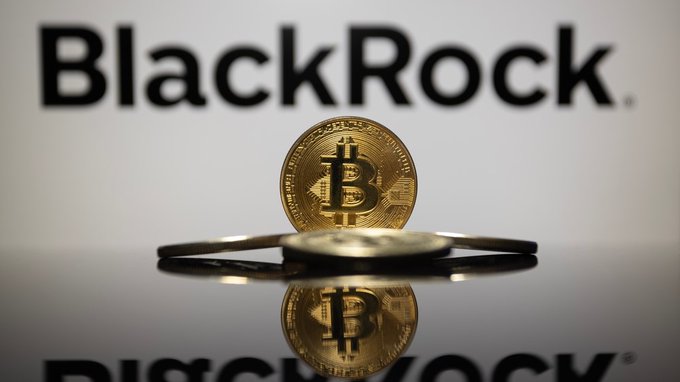 A physical Bitcoin token rests on a reflective surface in front of the "BlackRock" logo, visually reinforcing the post's announcement that BlackRock has lowered the minimum BTC in-kind conversion threshold to its IBIT ETF from $25M to $1M, with conversions now surpassing $5B.