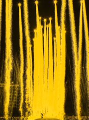 A yellow-tinted image showing what appears to be a firework display or bright lights descending like vertical streaks from the top of the frame.