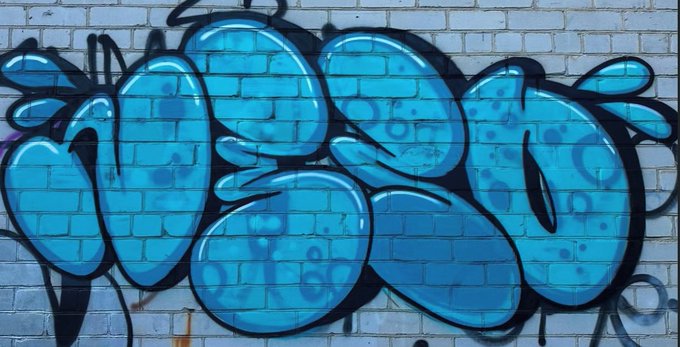 Vibrant blue graffiti-style bubble letters spelling "NESO" are spray-painted across a brick wall, showcasing the artwork of NesoArts, the NFT project being highlighted. The bold street art aesthetic reflects the project's creative style, tying directly to the promotion of its 5,000-supply mint at $1.52.