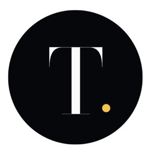 A circular black logo featuring a white serif letter "T" with a small yellow/gold dot positioned to the lower right of the letter.