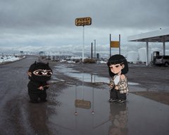 Two cartoon-like figures wearing black hats stand in a wet parking lot under an overcast sky near a gas station and a sign reading '58500'.