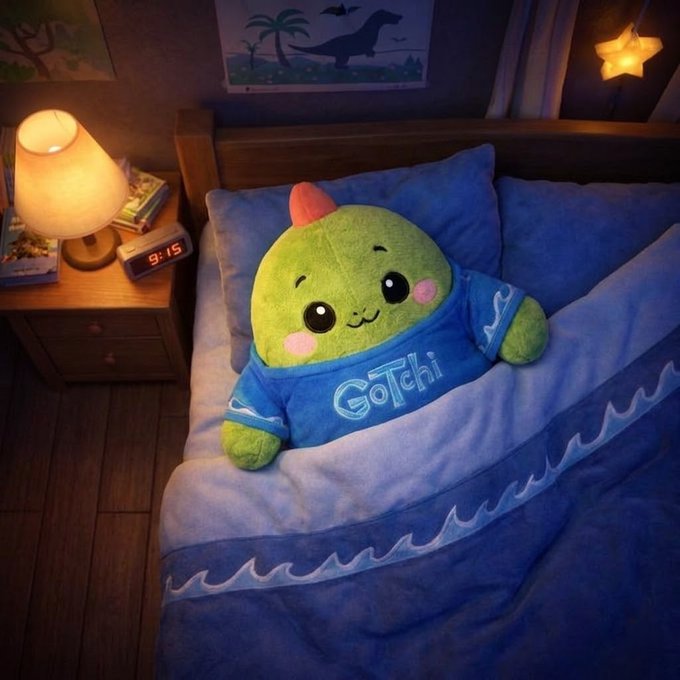 The image features a green stuffed animal, likely a GoTchi plush toy, lying down on a bed with blue sheets. The stuffed animal appears to be asleep or resting comfortably. The scene takes place at night, as indicated by the presence of a clock in the room and the dim lighting. The post about @sleepagotchi is related to this image because it highlights how GoTchi's unique features can be used for promoting healthy sleep habits. By incorporating GoTchi into one's nighttime routine or bedtime story, individuals may find that they are more likely to maintain a consistent sleep schedule and experience the benefits of quality rest.