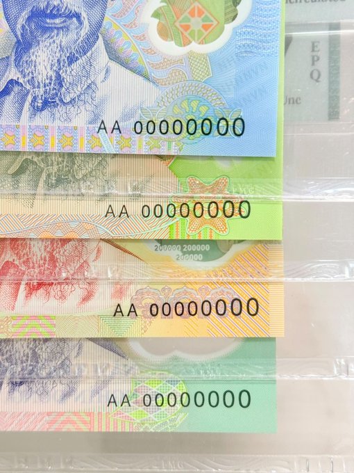Four overlapping novelty banknotes in plastic sleeves, each stamped with 'AA 00000000', appearing to be custom or sample currency notes in blue, green, orange, and green/blue designs.
