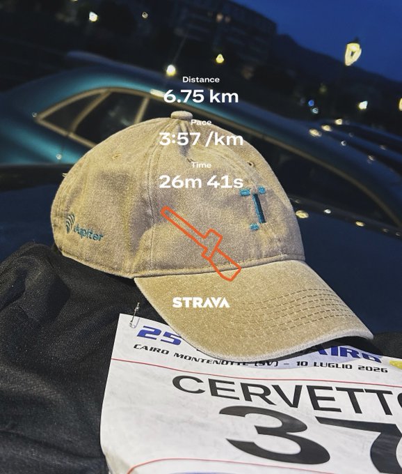 A worn beige 'Rapter' cap and a race bib numbered '37' for 'CERVETTO' lie on a dark surface, with a Strava overlay showing a 6.75 km run completed in 26m 41s.