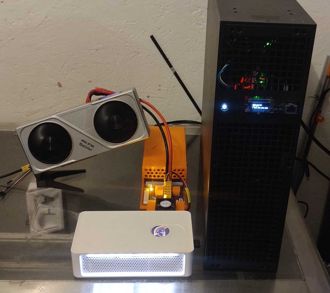 A cryptocurrency mining setup featuring a computer tower with a display, a power supply unit, a dual-fan cooling fan, and a Bitmain Antminer device.