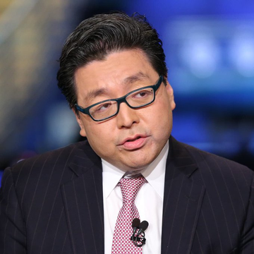 A man in a pinstripe suit and glasses, likely Tom Lee, speaks during a televised interview setting. The image relates to the post about Bitmine's continued aggressive Ethereum accumulation, with Tom Lee being a key figure associated with the company's crypto investment strategy.