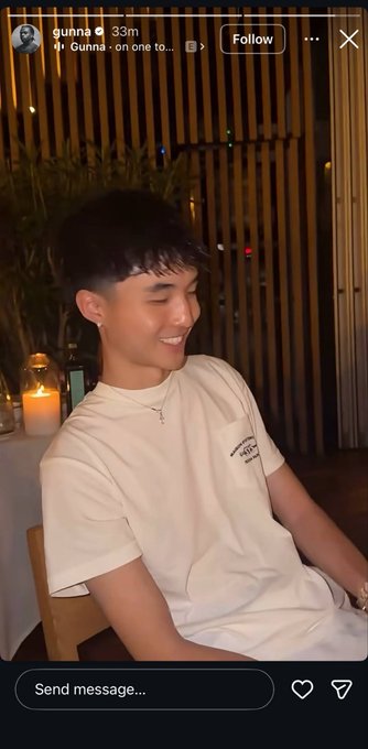 A young man smiles at dinner while wearing a cream T-shirt and cross necklace. The Instagram story is from “gunna,” posted 33m ago, with “Follow” and “Send message…” visible—an example of a celebrity’s public flex contrasting with the post’s point about discreet, high-level networking.