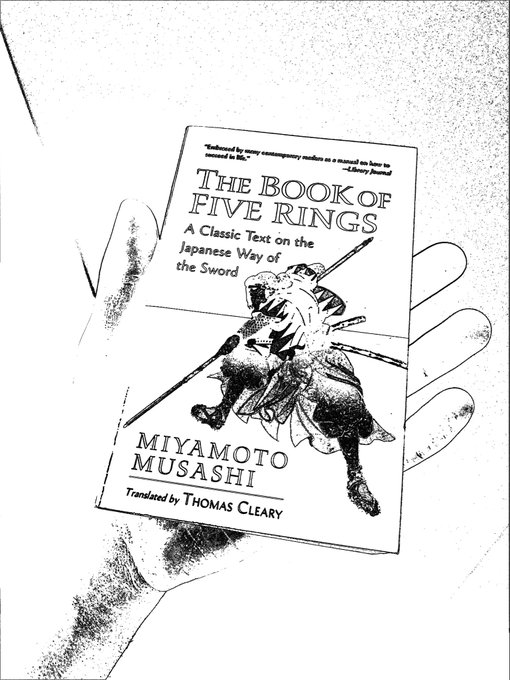 A hand holds a book titled 'The Book of Five Rings: A Classic Text on the Japanese Way of the Sword' by Miyamoto Musashi, translated by Thomas Cleary, featuring an illustration of a samurai on the cover.