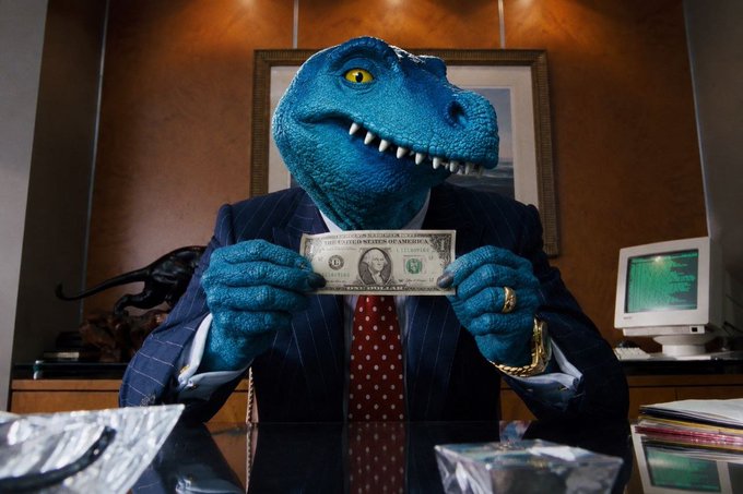 A person wearing a blue dinosaur mask and a pinstripe suit holds a United States one dollar bill in front of their face in an office setting with wood-paneled walls.