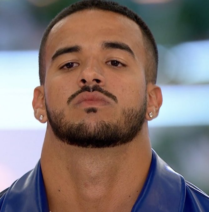 A man with a short beard and mustache, wearing a blue shirt and small earrings, stares upward with a tired, exasperated expression, perfectly capturing the reaction to a claim about ETHOS having 500k monthly users.