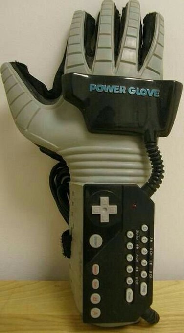 A vintage Nintendo Power Glove controller, featuring its iconic black and white design with a directional pad, buttons, and the 'POWER GLOVE' branding visible on the wrist portion.