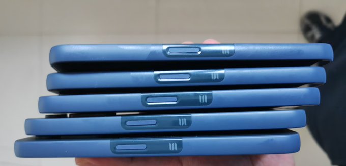 A close-up side view of five blue phone cases stacked on top of each other, showing the camera cutouts and side buttons.
