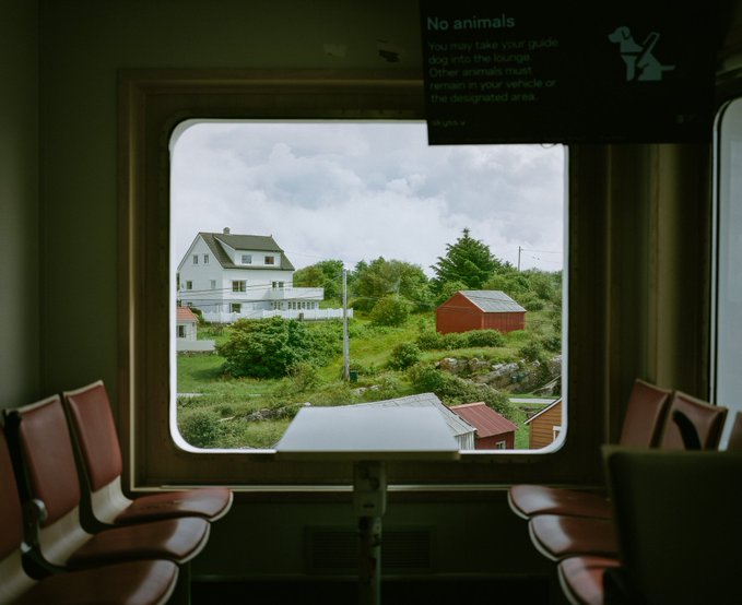 A view through a train window reveals a white house, red barn, and lush greenery in the distance, with a "No animals" sign visible above the window stating pets must be kept inside the vehicle. The "gm" caption likely refers to the scenic countryside greeting passengers as they travel.