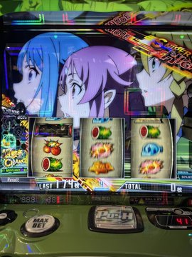 A Japanese pachislot/slot machine featuring anime characters with blue and pink hair above spinning reels displaying fruit symbols.