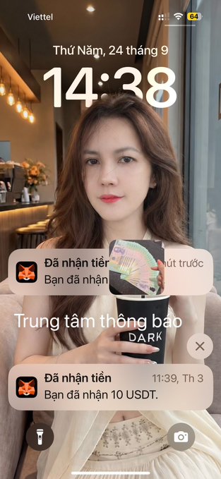 A phone lock screen showing the time 14:38 on Thursday, September 24, featuring a woman holding a phone with 'DARK' visible, and notifications in Vietnamese for received USDT payments at 'Trung tâm thông báo'.