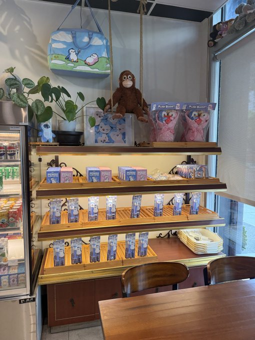 The interior of a Japanese souvenir or merchandise shop displaying various Petit Bunny plush toys, keychains, and merchandise on wooden shelves, with a Pepsi cooler on the left side.