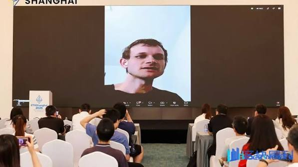 A video conference event in Shanghai, where an audience watches a man speaking on a large screen, with the word 'SHANGHAI' visible in the top left corner.