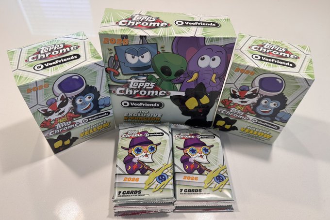 Several boxes and packs of "Topps Chrome 2026 Veefriends" trading cards, featuring colorful cartoon characters, with one box advertising an "Exclusive Wildcard Yellow Refractor" and two packs of "7 CARDS" in the foreground.