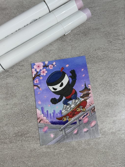 An artistic illustration card showing a black ninja-style figure skateboarding while wearing sneakers, with cherry blossoms and a pagoda in the background, displayed next to white marker pens.