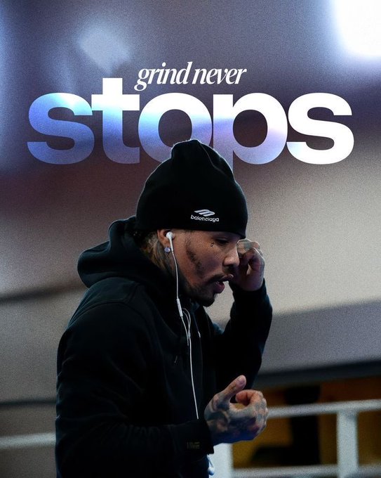 A man in a black hoodie and beanie stands with his head down, with the motivational text 'grind never STOPS' displayed in large blue and white letters above him.