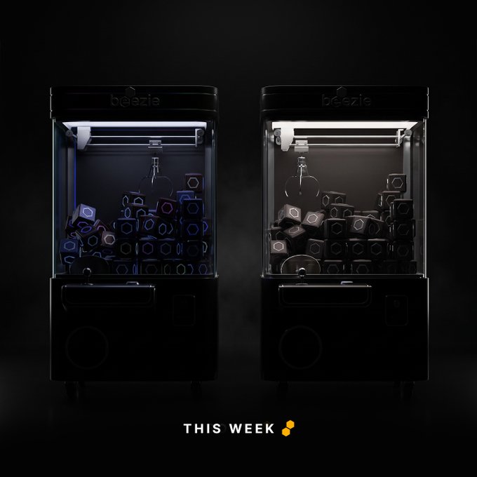 Dramatic product image of two 'beezie' claw machines filled with dark hexagonal pieces, with 'THIS WEEK' text at the bottom.