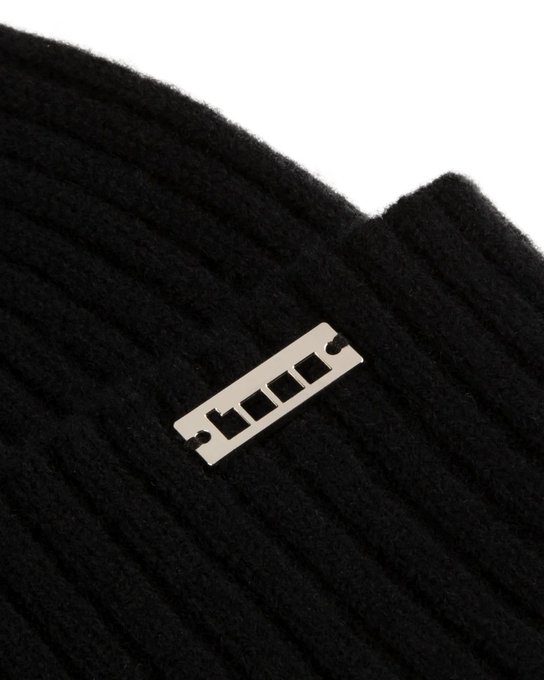 The image features a black knit hat with a silver metal tag attached to it. The tag has the letters "b" and "o" printed on it. The hat appears to be made of wool or a similar material, as it is described as a knitted cap in one sentence and a knit beanie in another. The image also contains text that reads: "gbase The future of onchain is being built on @base !" This message seems to be related to the hat with the metal tag attached to it, possibly indicating an upcoming innovation or development in the world of blockchain technology.