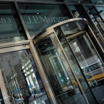 The image shows the entrance to a J.P. Morgan building, featuring the bank's name prominently displayed above a revolving glass door, with "383 Madison" partially visible. This ties directly to the news of J.P. Morgan's latest quarterly filing revealing its increased stakes in BlackRock's Bitcoin and Ethereum ETFs.