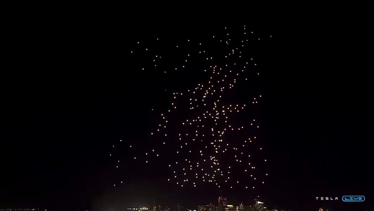 A large display of fireworks lit up against a dark night sky, with many bright sparks filling the air and capturing the viewer's attention. The image features several small fireworks scattered across the scene, creating an impressive visual effect. In the bottom right corner, there is a blue watermark that reads "$.DOGE".
