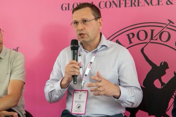 Dmitry wirex, co-founder and CEO of Wirex, speaks at the House of Block Web3 Talks & Polo panel discussion on Agentic AI, with the pink backdrop displaying "GLOBAL CONFERENCE & POLO" branding visible behind him as he addresses the audience while wearing a conference lanyard.
