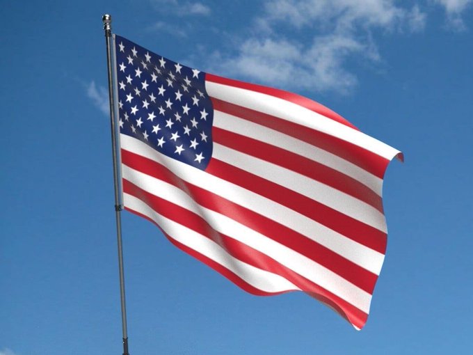 The American flag waves against a blue sky in this image, with no text or numbers visible. The accompanying post references the Federal Reserve's decision to leave interest rates unchanged at 3.5-3.75%, linking this image of the U.S. flag to the monetary policy announcement affecting American financial markets.