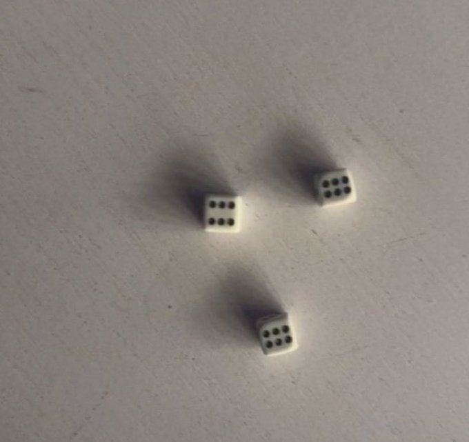 Three white dice showing six, six, and six dots on a textured white surface, forming an 18 (Yacht) roll.