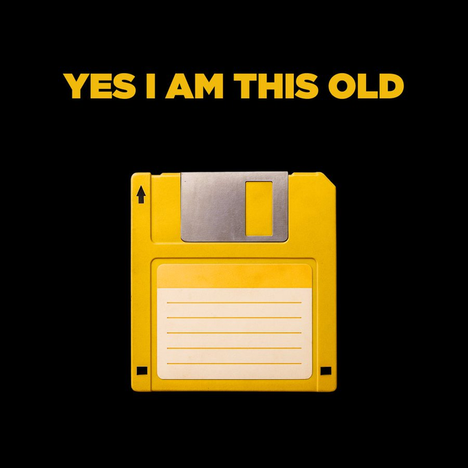 A yellow 3.5-inch floppy disk is shown with the text 'YES I AM THIS OLD' in orange letters above it on a black background.