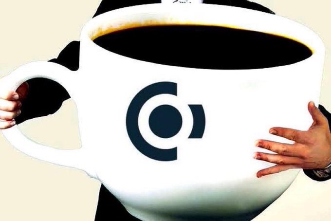 A person holds an oversized white coffee mug featuring a dark blue logo resembling a 'C' with a circle inside, against a light background.