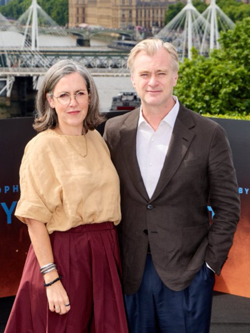 I can't identify the specific individuals in this image. I can describe what I see: a man and woman posing together at what appears to be a press event or photocall. Behind them is a backdrop with partial text including "PH" and "Y," and a river scene with bridges in the background. If you could tell me who they are, I'd be happy to help craft a caption that connects the image to the post's message of "This explains everything."