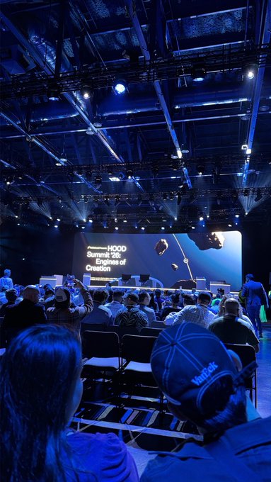 An audience at the HOOD Summit '24: Engines of Creation, seated in a large venue with blue lighting and a stage screen showing the event title.