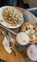 A slightly blurry photograph of an open menu or cookbook on a table, showing illustrations of pasta dishes, cutlery, and bread on plates.