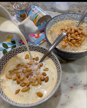 A bowl of garri (cassava flakes) being prepared with milk and groundnuts, alongside cans of Peak and Three Crowns milk, illustrating the breakfast that was quickly bought using naira obtained from a crypto-to-naira swap via Tonkeeper and Spenda.