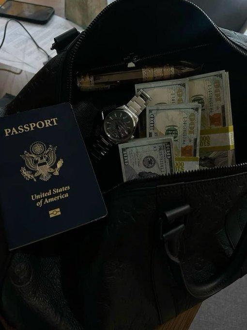 A U.S. passport, a silver wristwatch, and stacks of $100 bills are packed inside an open black travel bag. The image ties to the caption "GM - Another day another opportunity," symbolizing readiness for a new day of hustle and financial growth.